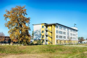 ein gelbes und weißes Gebäude neben einem Baum in der Unterkunft B&B HOTEL Baden-Airpark in Rheinmunster