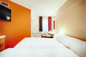 a hotel room with two beds and a desk at B&B Hotel Bonn-City in Bonn