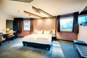 Schlafzimmer mit einem Bett, einem Schreibtisch und Fenstern in der Unterkunft B&B Hotel Bremen-City in Bremen
