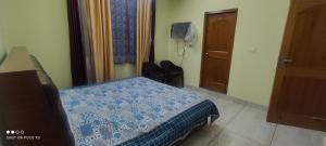 a bedroom with a bed with a blue and white comforter at Mahamaya Homestay 4 in Mandi