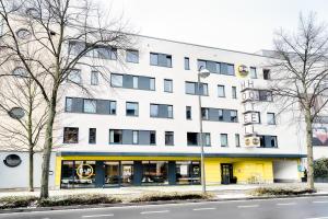 a large white building with a yellow facade at B&B Hotel Bonn-West in Bonn