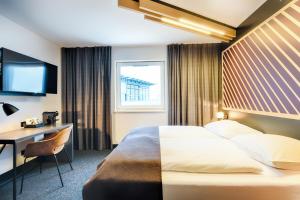 a hotel room with a bed and a desk and a window at B&B Hotel Bonn-West in Bonn