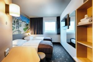 una camera d'albergo con due letti e un tavolo di B&B Hotel Bonn-West a Bonn