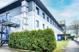 un edificio bianco con un cespuglio davanti di B&B Hotel Bielefeld-Ost a Bielefeld