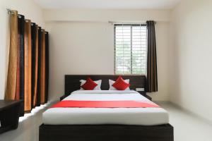 ein Schlafzimmer mit einem großen Bett mit roten Kissen in der Unterkunft Super OYO La Flora in Indore