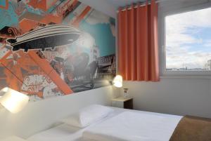ein Schlafzimmer mit einem Bett und einer Wand mit einem Wandbild in der Unterkunft B&B Hotel Böblingen in Böblingen