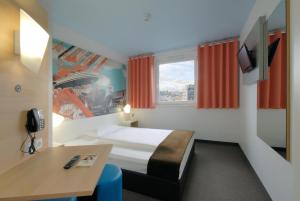 um quarto de hotel com uma cama, uma secretária e uma mesa em B&B Hotel Böblingen em Böblingen