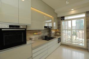 a kitchen with white cabinets and a large window at Artist House 3BR By Flora Stays in Mumbai