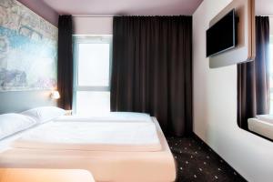 2 bedden in een hotelkamer met een flatscreen-tv bij B&B Hotel Eisenach in Eisenach