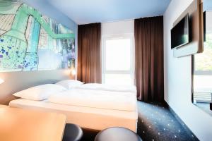 ein Hotelzimmer mit 2 Betten und einem TV in der Unterkunft B&B Hotel Chemnitz in Chemnitz
