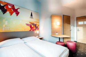 Un dormitorio con una cama blanca y una pintura en la pared en B&B Hotel Cuxhaven en Cuxhaven