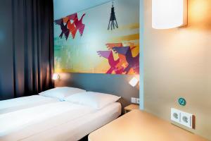 ein Hotelzimmer mit einem Bett und einem Gemälde an der Wand in der Unterkunft B&B Hotel Cuxhaven in Cuxhaven