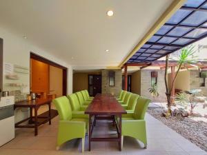 a dining room with a table and green chairs at Shinta Guesthouse in Malang
