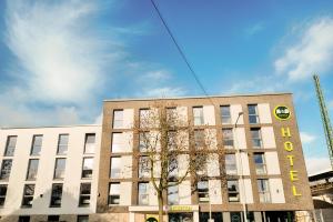 un edificio con un árbol delante de él en B&B Hotel Bochum-City, en Bochum