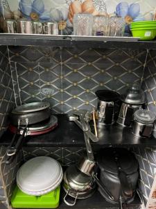 ein Regal mit Geschirr, Töpfen und Pfannen in einer Küche in der Unterkunft John Beach House in Puducherry