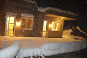 a house covered in snow in front of a house at Bauhaus Chalets Apartment in Bcharré