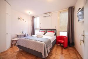 a bedroom with a bed and a red chair at Sea Organ Apartment 2 (Oldtown Studio) in Zadar