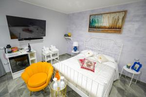 a bedroom with a white bed and a yellow chair at Piedigrotta Magique Luxury in Pizzo