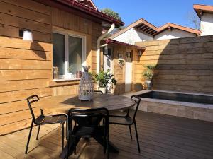 una mesa de madera y sillas en una terraza de madera en FLEUR DES PINS Maison tout confort au calme, en Arcachon