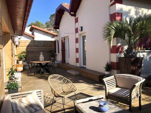 a patio with chairs and a table in a house at FLEUR DES PINS Maison tout confort au calme in Arcachon