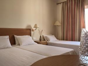 a hotel room with two beds and a window at Strada Marina Hotel in Zakynthos