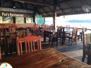 ein Restaurant mit Holztischen und -stühlen sowie Tischen und Stühlen in der Unterkunft Pon's Riverside Guesthouse in Muang Không