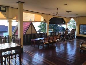 Muang Không的住宿－Pon's Riverside Guesthouse，餐厅铺有木地板,配有木桌和椅子