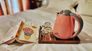 a tea kettle and a book on a bed at La vaccanza Suite -403 in Pune