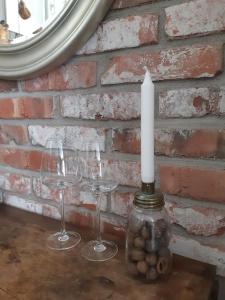 a candle and three wine glasses in front of a brick wall at Alapihan Arboretumin vierasmaja ja sauna 