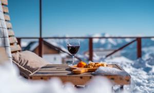 a glass of wine and a plate of food on a table at Alpina Hotel in Gudauri