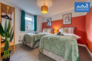 two beds in a room with red walls at 4 Bed Design House, 2 Off-road Parking Spaces, Great for Groups - Central Gloucester By Blue Puffin Stays in Gloucester