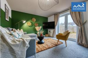a living room with green walls and a couch and a tv at 4 Bed Design House, 2 Off-road Parking Spaces, Great for Groups - Central Gloucester By Blue Puffin Stays in Gloucester