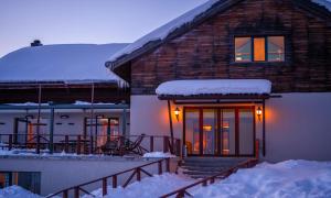 a house with snow on the roof and lights on the door at Alpina Hotel in Gudauri