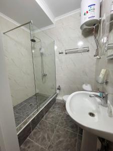 uma casa de banho com um chuveiro e um lavatório. em Hotel Nova em Bishkek