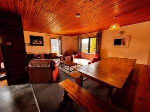 a living room with a wooden ceiling and a table at Snowgoose Apartments & Bunkhouse in Fort William