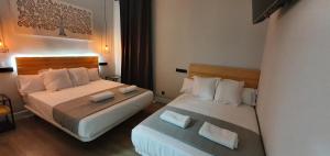 a hotel room with two beds with towels at CH Lemon Rooms - Madrid in Madrid