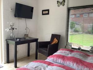 een slaapkamer met een bureau, een stoel en een televisie bij Dekker in Nijverdal
