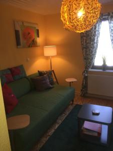 sala de estar con sofá verde y lámpara en Sunshine Cottage, en Waldsolms
