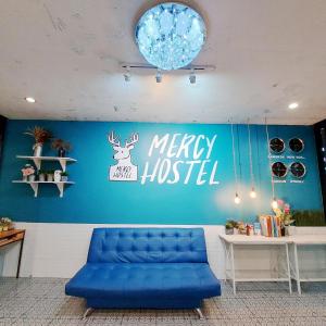 a blue couch in a room with a merry hospital sign at Mercy Hostel in Chiang Rai