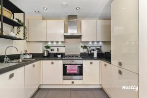 a kitchen with white cabinets and a stove at Puffin Way - Comfortable, spacious house with parking in Reading