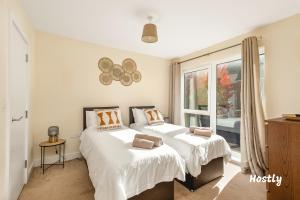 a bedroom with two beds and a window at Puffin Way - Comfortable, spacious house with parking in Reading