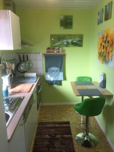 a kitchen with a table and a green wall at Sunshine Cottage in Waldsolms