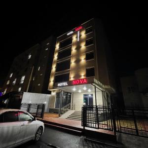 a nova building with a car parked in front of it at Hotel Nova in Bishkek