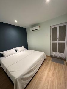 a bedroom with a large white bed and a blue wall at CT HOME83Stay - Klebang Beach Melaka in Kelebang Besar