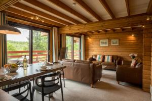 a living room with wooden walls and a table and chairs at Thistle Lodges at Sandyhills Bay in Dalbeattie