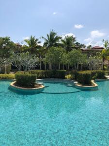 a swimming pool with blue water and palm trees at Phuket Laguna Beach - Big Family Pool Villa 2 Extra Large bedrooms in Layan Beach