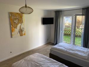 een slaapkamer met 2 bedden, een tv en een raam bij Monteurswohnung mit kleinem Garten 600M zur Stadtmitte in Siegen