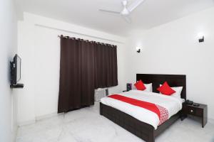 een slaapkamer met een groot bed met rode kussens bij Super OYO The Primero Near Leisure Valley Park in Gurgaon