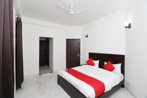 1 dormitorio con 1 cama grande con almohadas rojas en Super OYO The Primero Near Leisure Valley Park, en Gurgaon