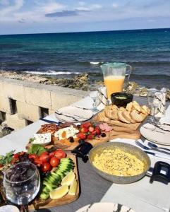 Ayyorgi的住宿－High By The Beach House in Girne，一张桌子,桌子上放着食物,靠近大海